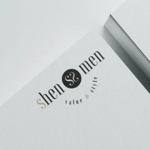 Shenmen logó bézs és fekete színekben. Középen a két S betű egymás felé fordul és egy stilizált szívet jelenít meg egy fekete körben. Elegáns, letisztult összhatás.